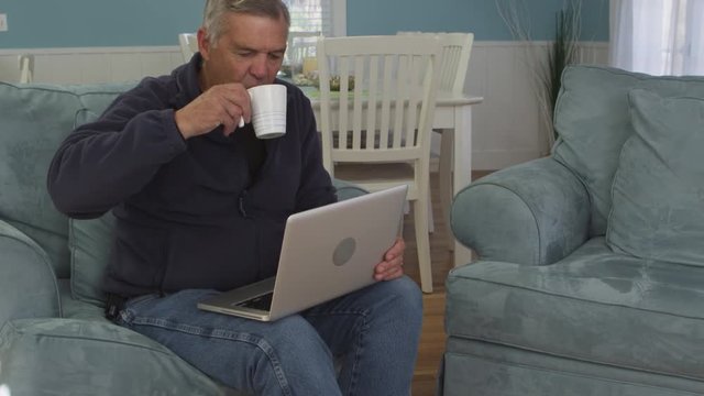 Middle aged man using laptop at home - 4K