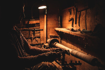 An artisan carves a piece of wood using a manual lathe