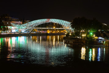 Fototapeta na wymiar Bridge of Peace reflected in river Mtkvari (Kura). Tblisi, Georg