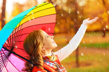 happy woman with rainbow multicolored umbrella under rain in par