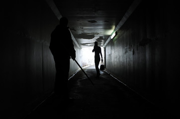 Man harassing a woman in a dark tunnel