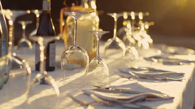 Laying out of the elegant dinner table for wedding celebration. Outside shooting. No people around. Only glasses and wine are glancing on the sunshine. Camera stabilizer shot.