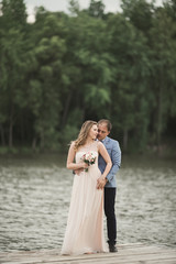 Beautiful wedding couple, bride,groom kissing and posing on the bridge near lake