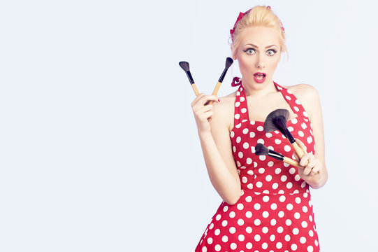 Girl makeup holding brushes with a pin up red dress