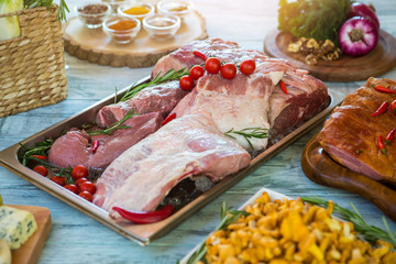 Raw meat pieces and ice. Small tomatoes and herb. Fresh pork for steaks. Table in the restaurant kitchen.
