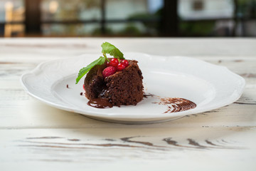 Dessert with mint leaf. Raspberry and red currant. Sponge cake with liquid chocolate. Sweet baked product.