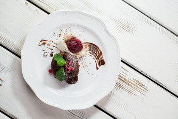 Dessert with ice cream. Spun sugar and fresh berries. Sponge cake with chocolate filling. Sweet dish on kitchen table.