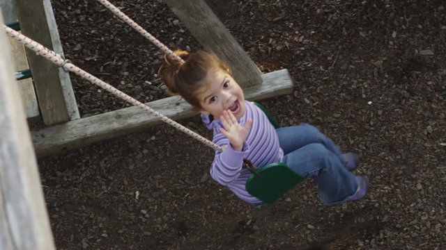 Slow motion shot of young girl on swings - 4K