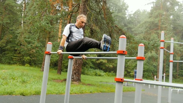 A man does push-ups on parallel bars