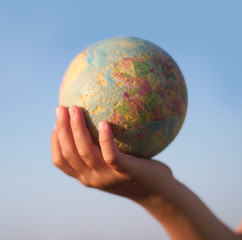 Child hand holding an earth toy globe