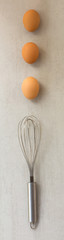 eggs are laid in a row and steel whisk on a gray background
