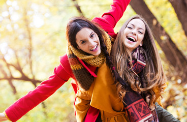 Two beautiful young women enjoying in the park on an autumn day 