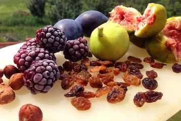 Photograph of plums, figs, blackberries, hazelnuts and raisins on white platter