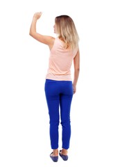 Back view of beautiful woman welcomes. backside view of person. Isolated over white background. Blonde in blue pants writes chalk