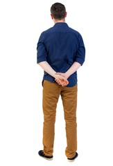 Back view of man . Standing young guy. man in a blue shirt with the sleeves rolled up, standing with his hands behind his back..