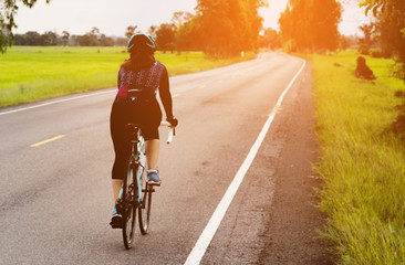 Women cycling on the road morning day - sport bike concept