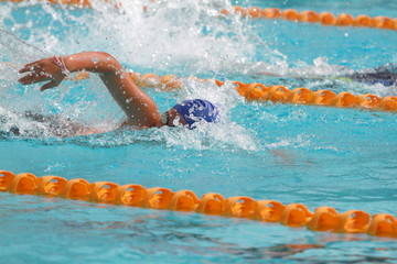 Young swimmer wearing blue cap practice freestyle stroke in a swimming pool for competition or race © wibulpas