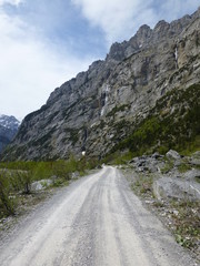 Deserted gravel road in the Gasterntal mountain valley, Switzerland, with jagged peaks rising steeply up from the valley floor