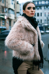 The girl is in a fur coat on the street