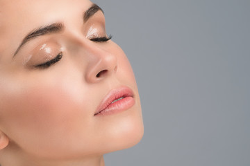Portrait of a young girl's face with perfect skin and nude wet make up. Skin care concept. Close...