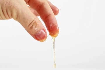 honey flows from the fingers on white background