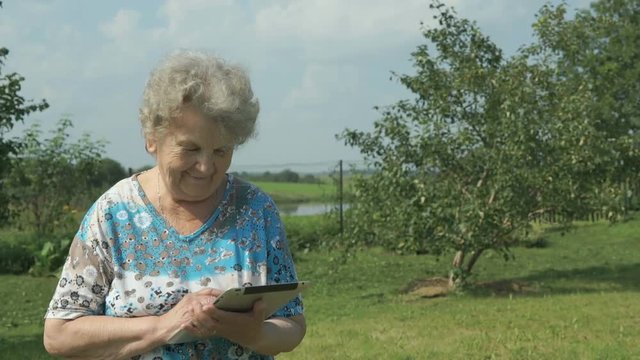 Ederly woman holding a digital tablet outdoors
