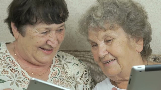 Two elderly grandmothers holding digital tablets