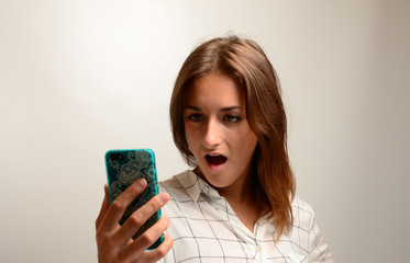junges Mädchen starrt erschrocken auf ihr Handy