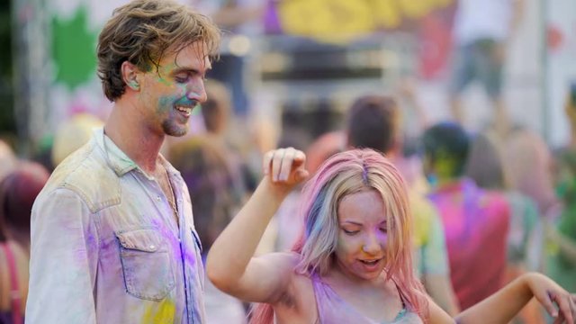 Girl kissing boyfriend, cheerful couple dancing to music in crowd at concert