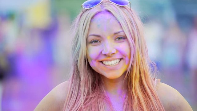 Excited face of happy young lady smiling to camera, having fun at Holi festival