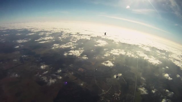 Skydivers freestyle in cloudy sky. Extreme sport. Sunny day. Above land. Adrenaline