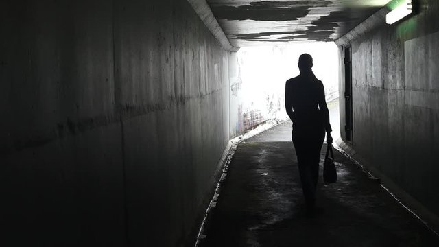 Silhouette of a man thief ambush steals a bag from a woman in a dark tunnel. Violence against women concept. Real people, copy space