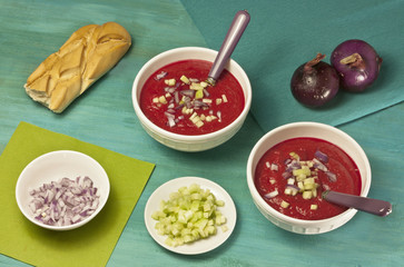 Two bowls of beetroot gazpacho with garnish and bread