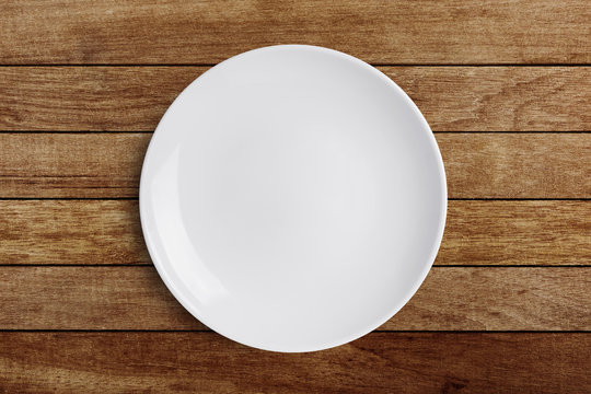 Simple white circular porcelain plate on wood background