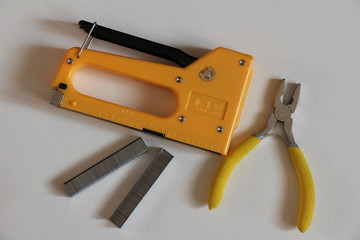 Yellow stapler, yellow pliers and staples. Everyday instruments and tools