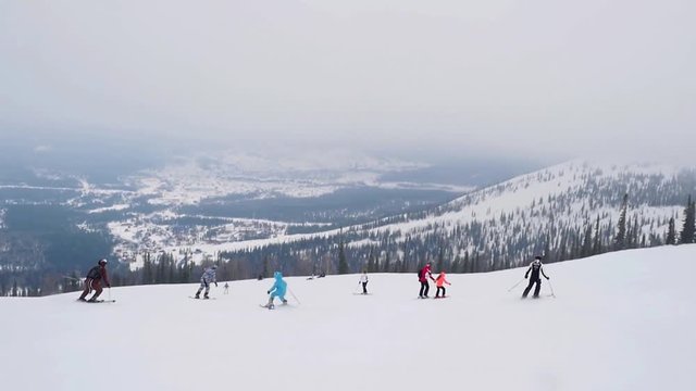 happy skiers and snowboarders on the slope at a ski resort in the Alps in slowmotion in a snowstorm. 1920x1080
