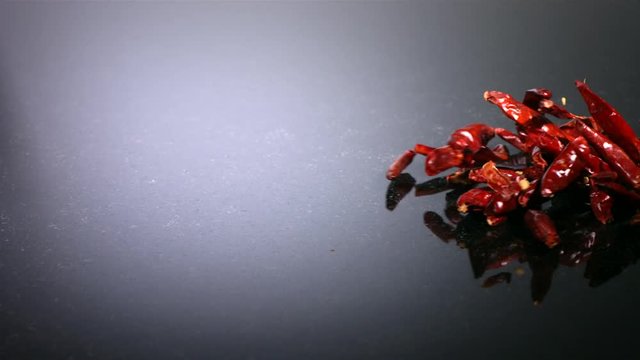 Slow motion shot of red chilli peppers on tabletop