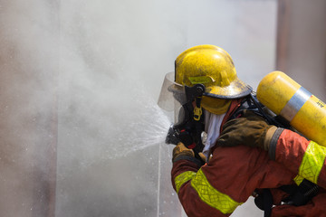 firefighter in fire protection suit spraying water to fire 