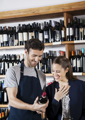 Salesman Showing Wine Bottle To Happy Female Customer