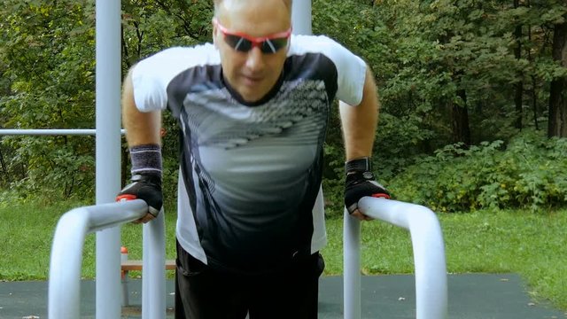 A man does push-ups on parallel bars