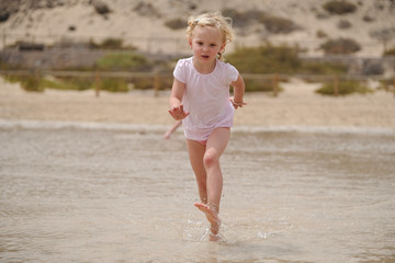 Fototapeta na wymiar blondes Mädchen rennt am strand