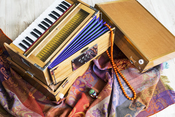 Indian harmonium, a traditional wooden keyboard instrument, close-up.  Bright colorful musical instrument on the patterned wrap