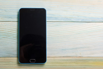 Smartphone with blank area on touch screen rustic wood blue table at outdoor in morning time, high...