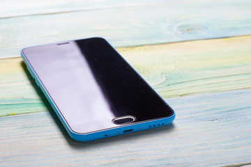 Smartphone with blank area on touch screen rustic wood blue table at outdoor in morning time, high...