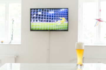 Elfmeter beim Fußball als Fernsehbild und ein Weißbier auf einem Tisch