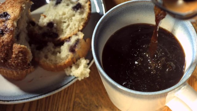 Slow motion overhead shot of coffee and muffin on breakfast table