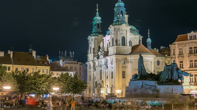 Baroque St. Nicholas' Cathedral on the Oldtown Square in Prague with monument Jan Hus illuminated at night timelapse