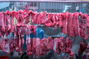 Hanging pork and meat at butcher shop stall at fresh food market in Asia, Freshly slaughtered meat...