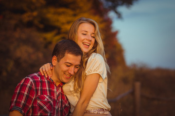 Man raises his pretty girl while leaning to wooden fence
