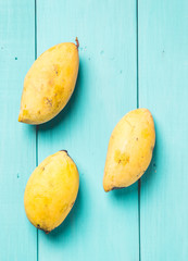 Ripe mangoes on light green blue wood table
